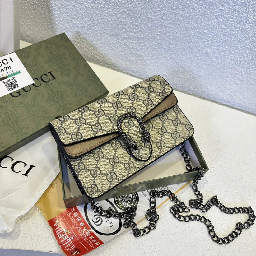 Designer handbag with chain detail on a textured surface with Gucci packaging.
