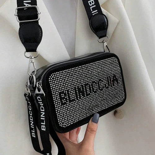 Black studded handbag with 'BLINDCIA' branding held by a hand against a white background