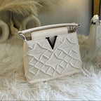 White handbag with decorative pattern on a fluffy white surface