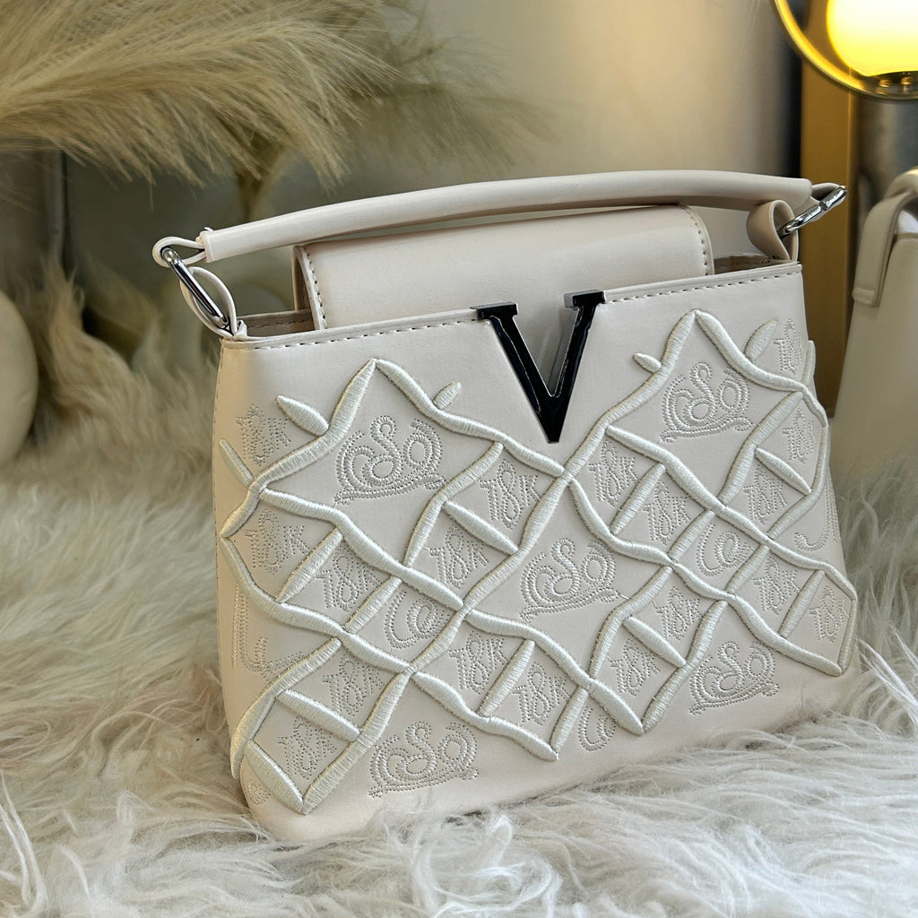 White handbag with intricate design on a fur surface