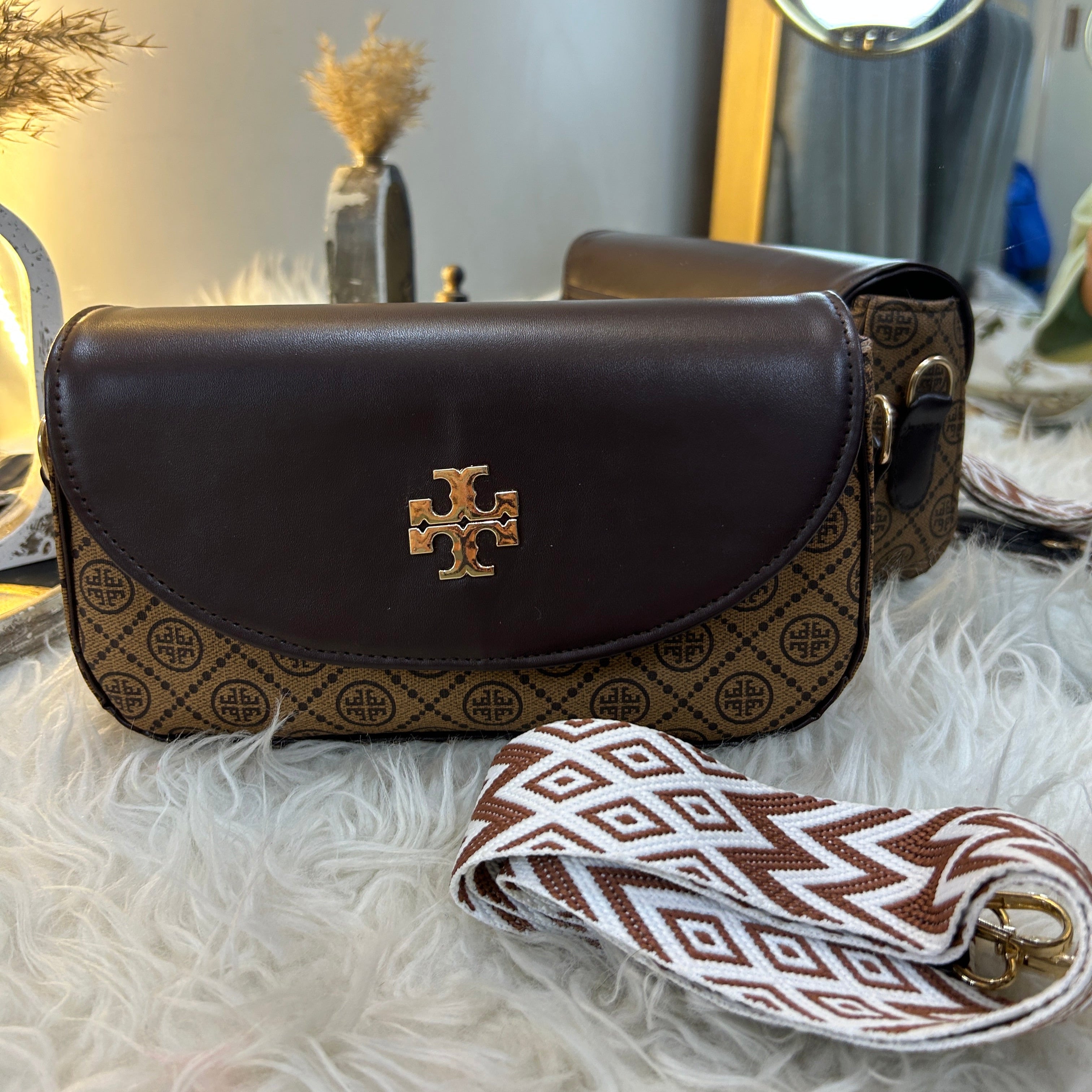 Brown leather pouch with patterned strap on a textured surface