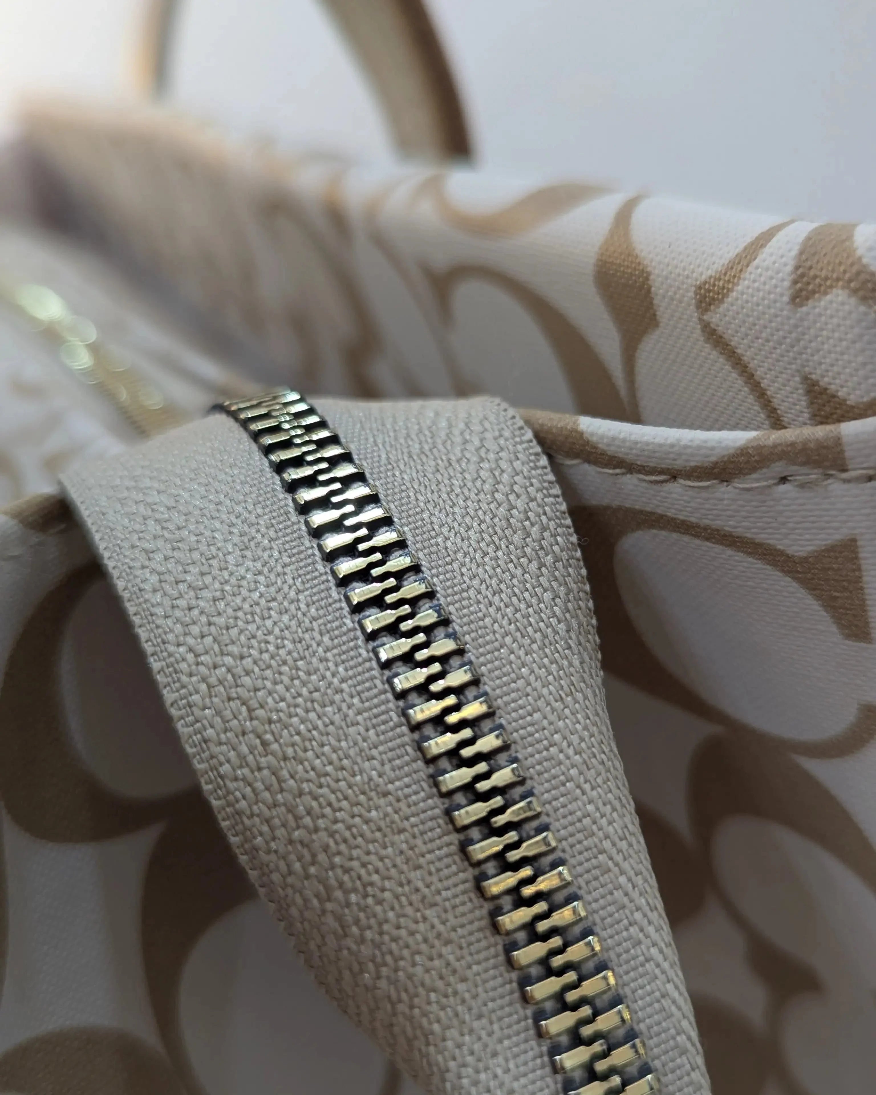 Close-up of a gold zipper on a beige fabric background