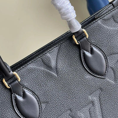 Close-up of a black handbag with gold hardware on a neutral background