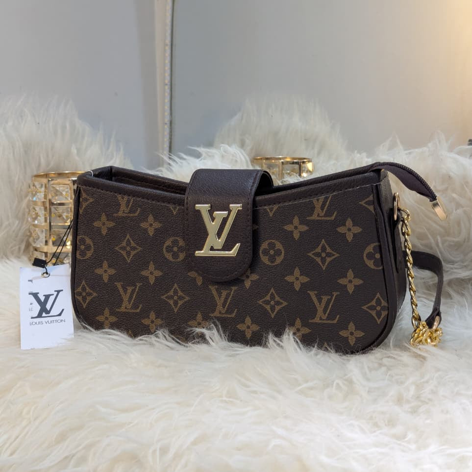 Designer handbag with monogram pattern on a fluffy surface, with a blurred indoor background.