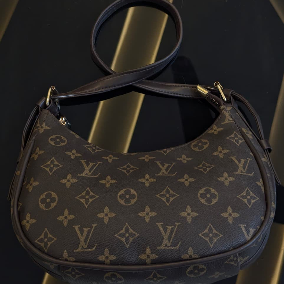 Designer handbag with monogram pattern on a reflective surface
