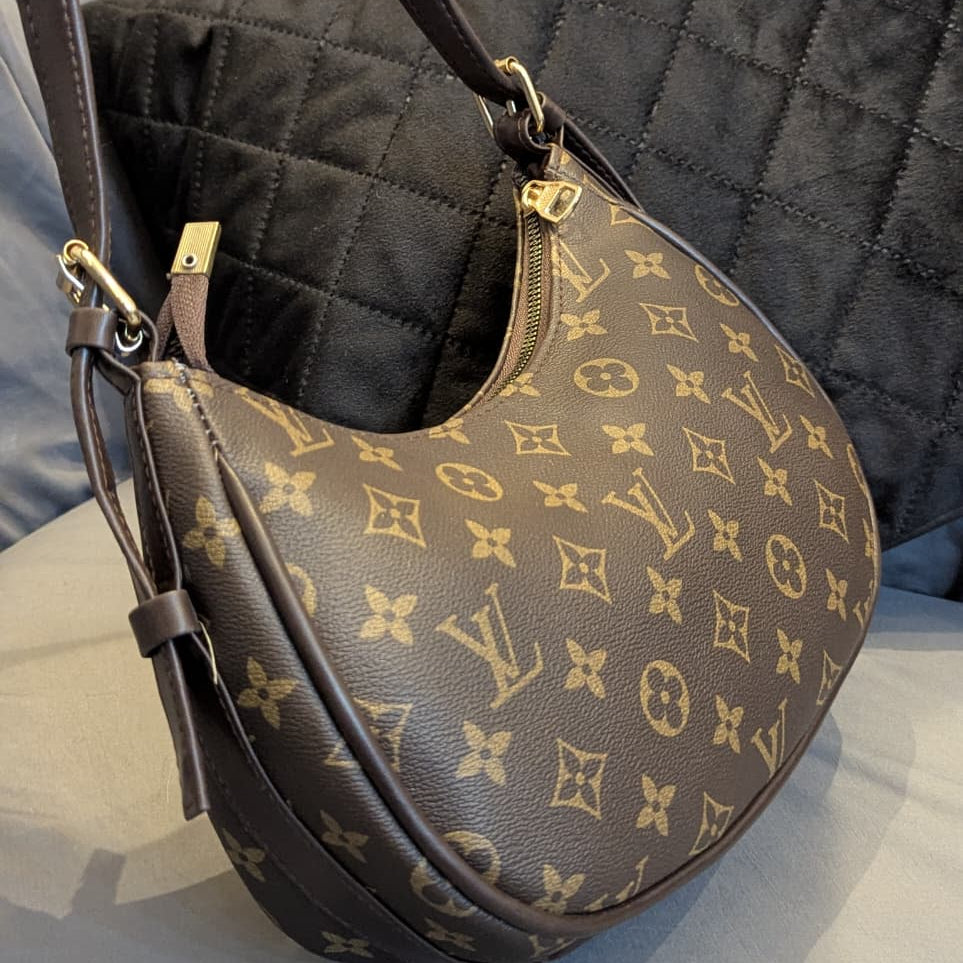 Designer handbag with monogram pattern on a reflective surface