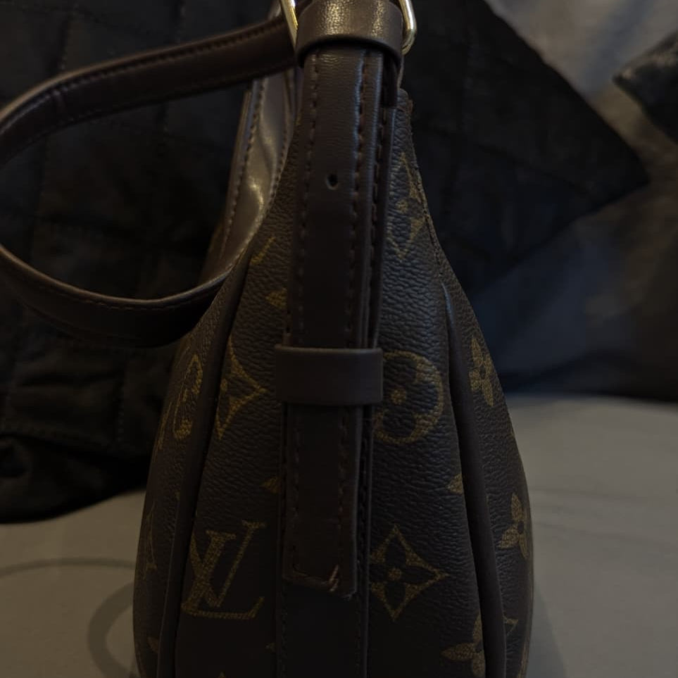 Brown leather handbag with gold buckle on a reflective surface