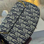 Designer handbag with brand logo pattern held by a hand on a soft surface.