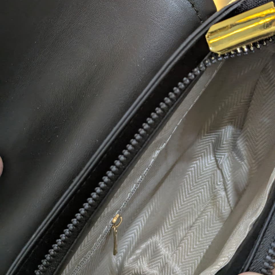 Close-up of a black leather bag with a zipper, showing the interior lining.
