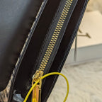 Close-up of a black handbag with a gold zipper on a blurred background