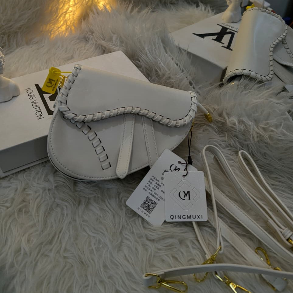 White handbag with a visible brand tag on a fluffy white surface.