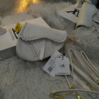 White handbag with a visible brand tag on a fluffy white surface.