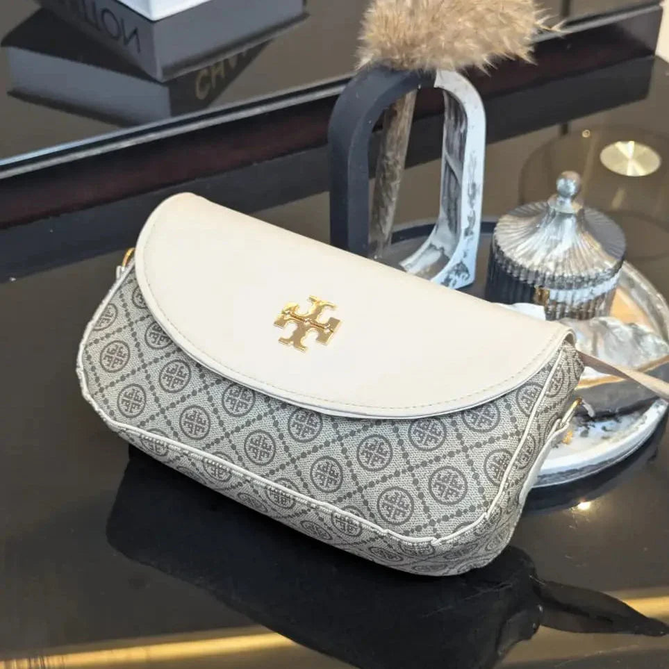 Patterned handbag with gold logo on a reflective surface