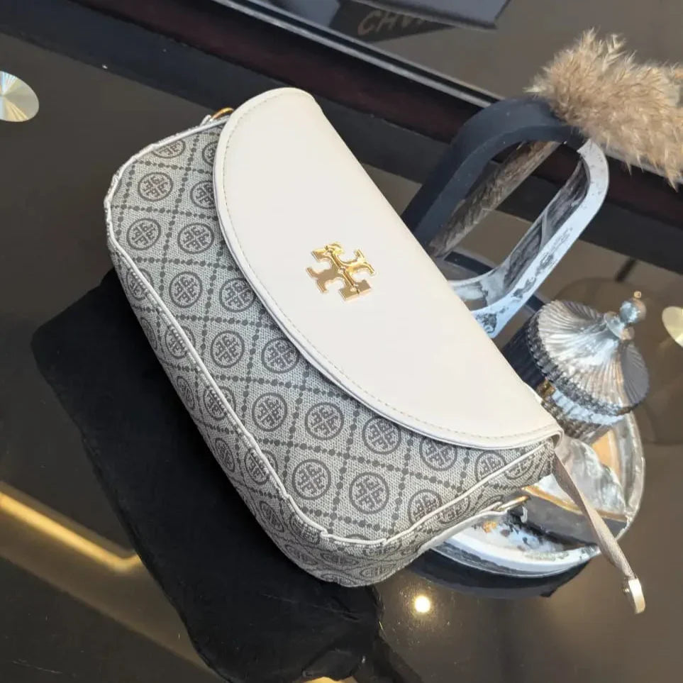 Patterned pouch with gold emblem on a reflective surface