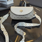 Designer handbag with a patterned strap on a reflective surface