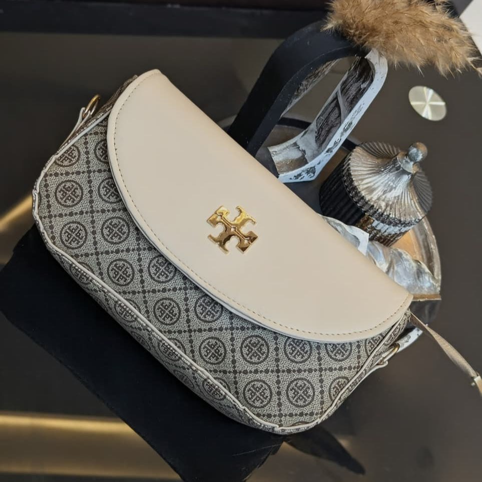 Patterned handbag with a gold emblem on a reflective surface