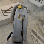 White handbag with gold accents on a textured surface